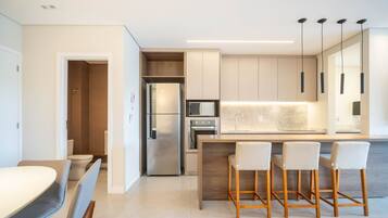 Uma cozinha moderna com ilha central, banquetas e eletrodomésticos embutidos.