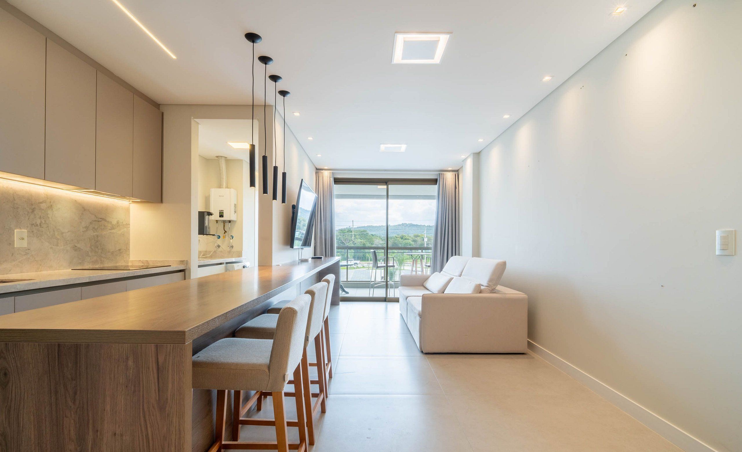 Cocina moderna con una isla central, taburetes de bar y vistas al exterior.
