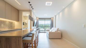 Cocina moderna con una isla central, taburetes de bar y vistas al exterior.