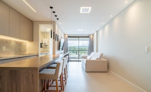 A modern kitchen with a central island, bar stools, and a view of the outdoors. - Apt With Balcony and Barbecue in Jurere Ihd0101 (Florianópolis)