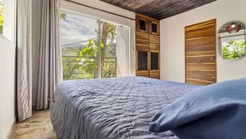 Un dormitorio con una cama grande, un armario de madera y un ventanal con vistas a zonas verdes.