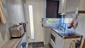 A compact kitchen with a built-in stove, a toaster, and a window with a view.