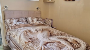 A bedroom with a large bed featuring intricate dragon and cloud designs, a headboard, and artwork on the walls.