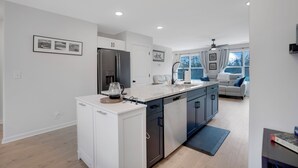 A modern kitchen with white cabinetry, a stainless steel refrigerator, and a built-in dishwasher.