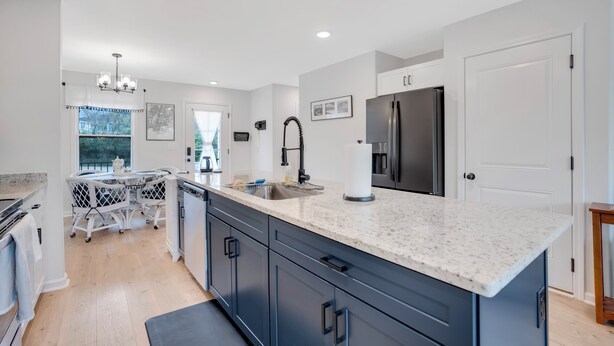 A modern kitchen with a large island, stainless steel appliances, and a view of the outdoors.