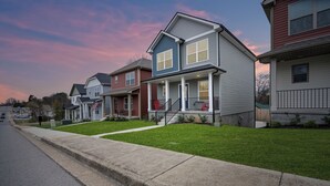A row of townhouses with front porches, a sidewalk, and a street.