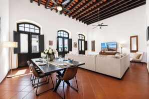 A spacious living area with a dining table, sofa, and TV.