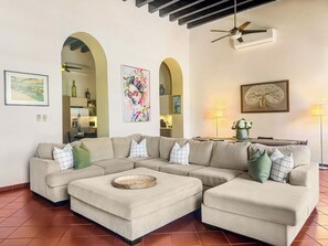 Una sala de estar con un sofá modular, una mesa de centro y un comedor con una lámpara.