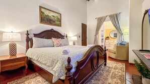 Une chambre à coucher avec un lit en bois, une table de chevet, une lampe, un tableau au mur et une vue sur la salle de bain.