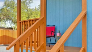A wooden staircase leading to a covered outdoor area with a blue wall and a red chair. - Central Tucson Studio Paradise (Tucson)