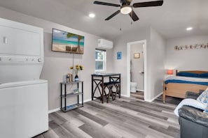 A compact hotel room with a kitchenette, a dining area, and a bed.