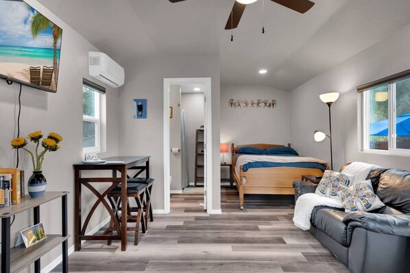 A compact hotel room with a bed, a sofa, a desk, and a TV.