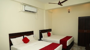 A hotel room with two beds, a ceiling fan, an air conditioning unit, and a wardrobe.