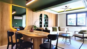 A modern living room with a dining area, featuring a round wooden table with black chairs, a sofa, and a coffee table. - Flex Ortaköy (İstanbul)