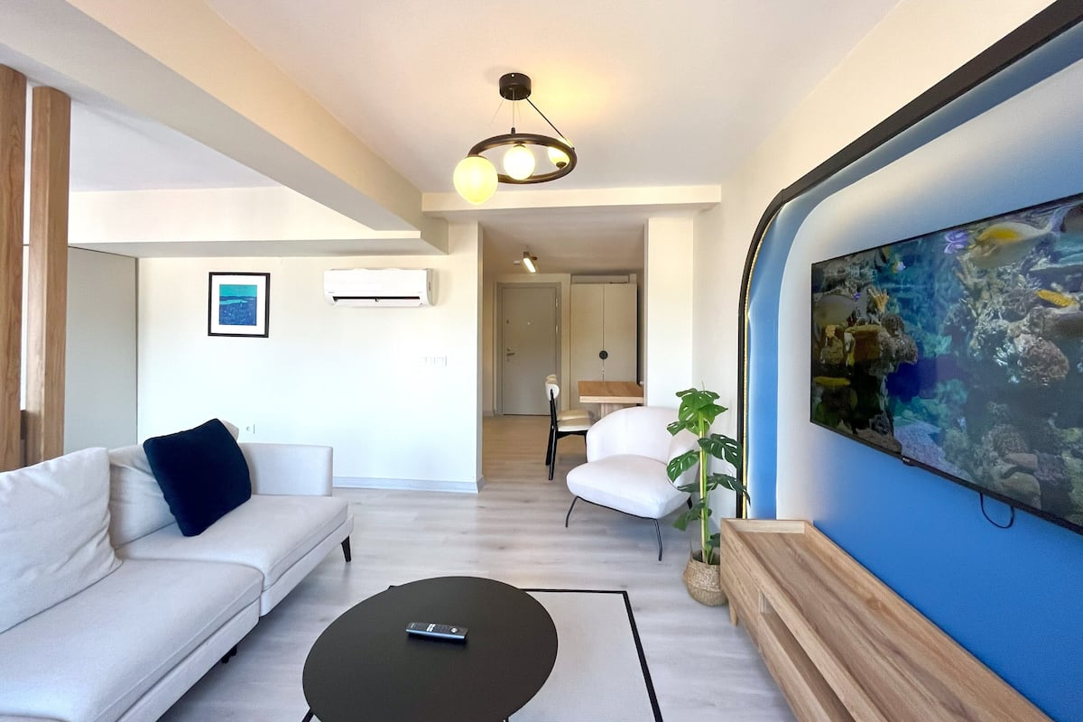 Una sala de estar moderna con un sofá, una mesa de centro y un televisor montado en la pared.