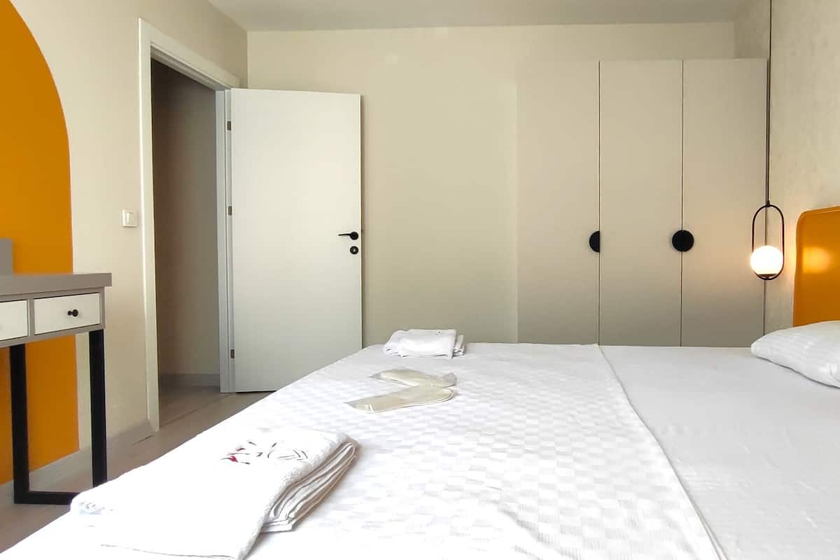 Una habitación de hotel con cama, mesita de noche, espejo y armario.