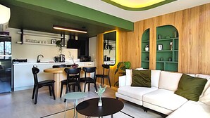 A modern living room with a white sofa, black chairs, a small round table, and a green plant. - Flex Ortaköy (İstanbul)