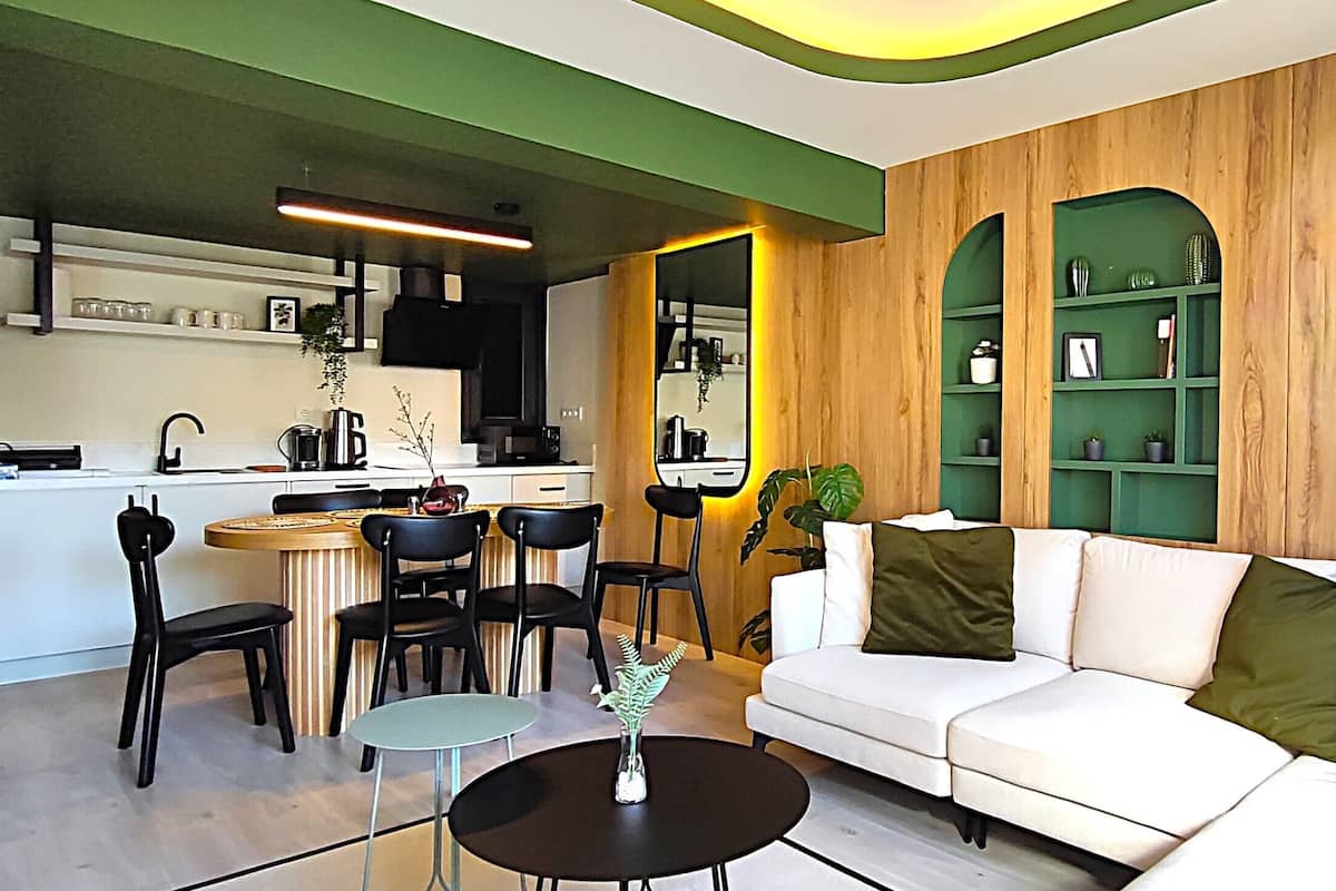 Una sala de estar moderna con un sofá blanco, sillas negras, una mesa redonda pequeña y una planta verde.