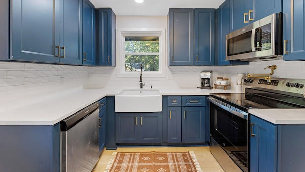 A modern kitchen with blue cabinets, a stainless steel microwave, and a built-in oven. - {Renovated 2BR in CLT – Where Location, Comfort & Mild Bragging Rights Collide} (Charlotte)