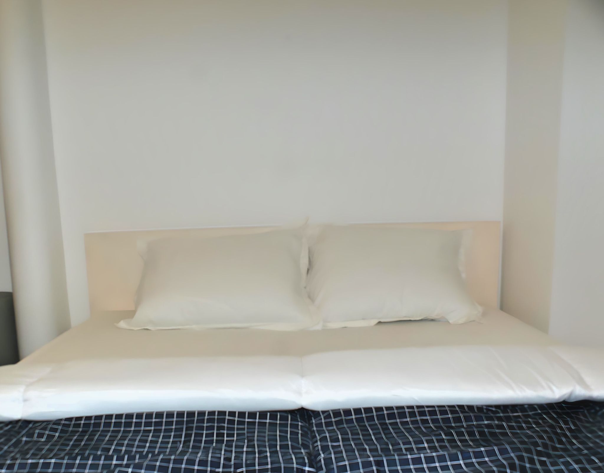 A bed with a white headboard and two pillows.