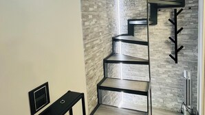 A modern interior with a staircase, a bench, and a wall-mounted light fixture.