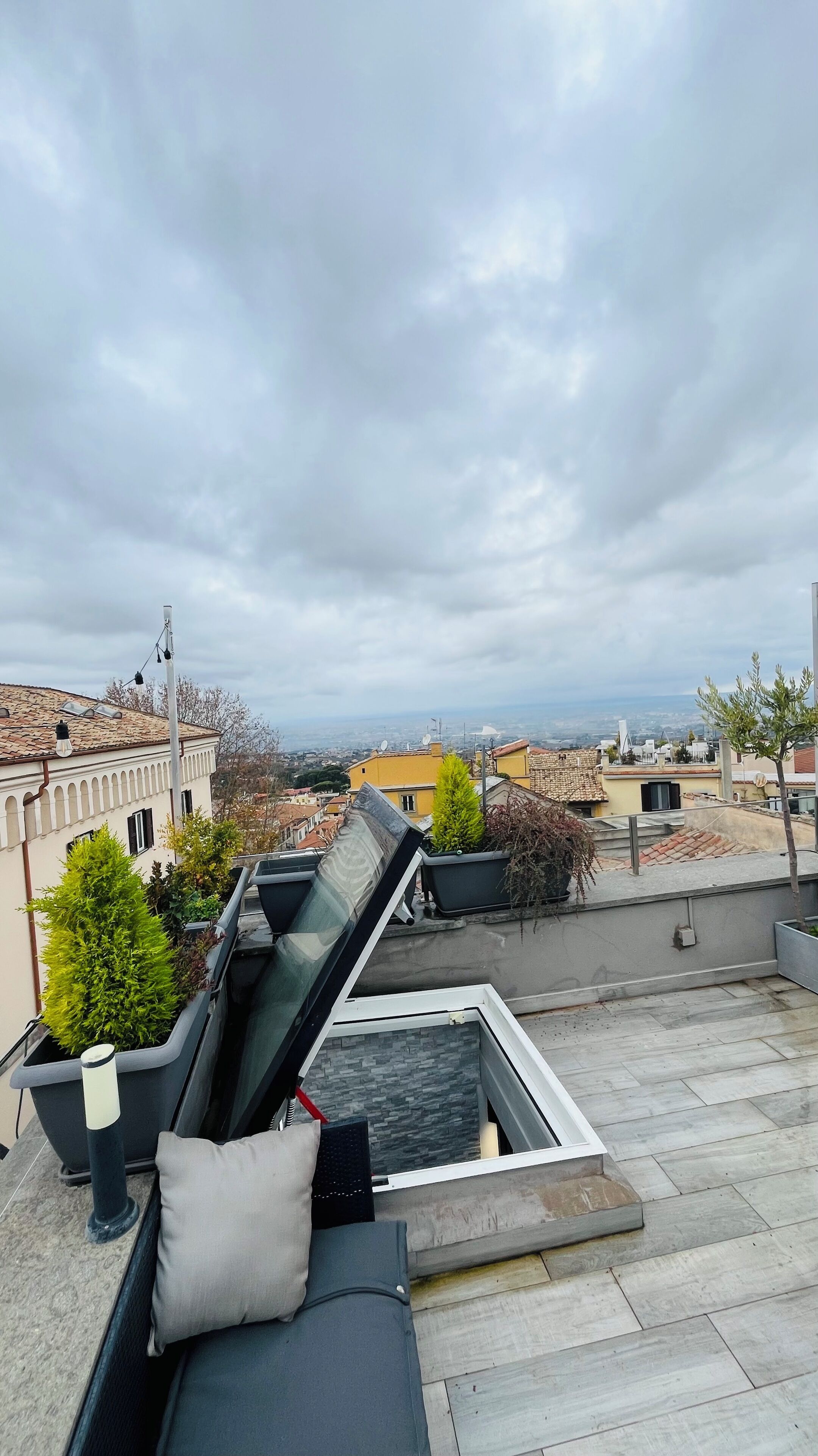 Una terraza en la azotea con piscina, sillas de descanso y vistas a la ciudad.