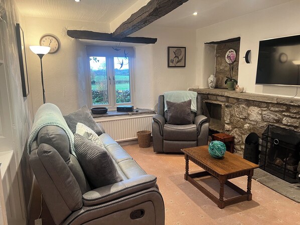 A cozy living room with a sofa, armchair, and a fireplace. - The Old Farmhouse at Brackenthwaite Farm (Carnforth)