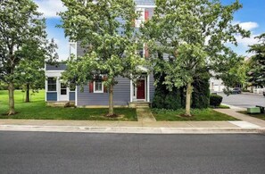 A residential building with a private entrance, surrounded by trees and a well-maintained lawn.