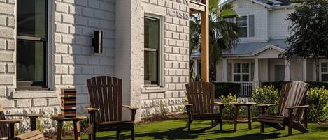 A patio area with outdoor furniture, a brick wall, and a white building in the background.