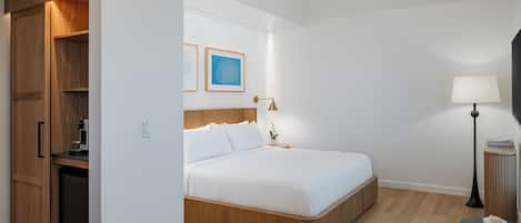 A hotel room with a bed, bedside table, lamp, and a wooden wardrobe.