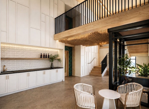 A modern kitchen with white cabinetry, a black countertop, and a wooden staircase. - The Livery Guesthouse (Tarpon Springs)