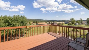 Una terraza de madera con vistas a un paisaje rural, que incluye casas y árboles.