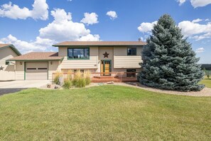 A two-story house with a garage, a front porch, and a large evergreen tree.