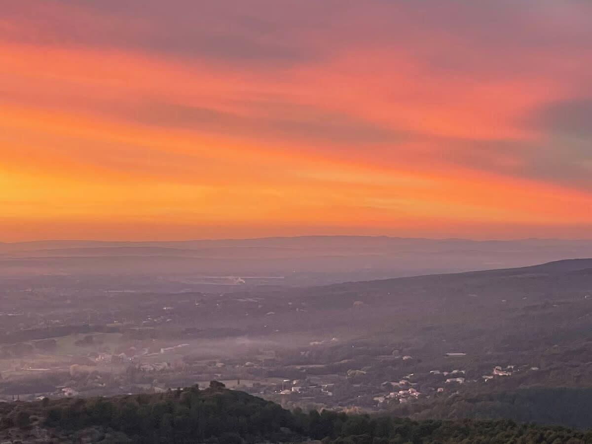 A panoramic view of a valley with a sunset sky.