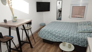 Ein Schlafzimmer mit einem Bett, einem Schreibtisch mit zwei Stühlen, einem Fernseher und einem kleinen Tisch mit zwei Tassen.