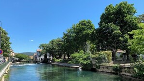 Ein Fluss mit einer Brücke, Bäumen und Gebäuden entlang des Ufers.