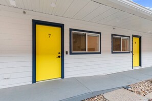 A row of three motel rooms with yellow doors and windows, numbered 6, 7, and 8, along a concrete walkway. - Queen City Inn and Extended Stay #8 (Spearfish)