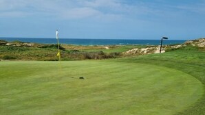 A golf course with a flagstick, a flag, and a flagpole. - Casa Del Rey - Golf and Beach (Amoreira)