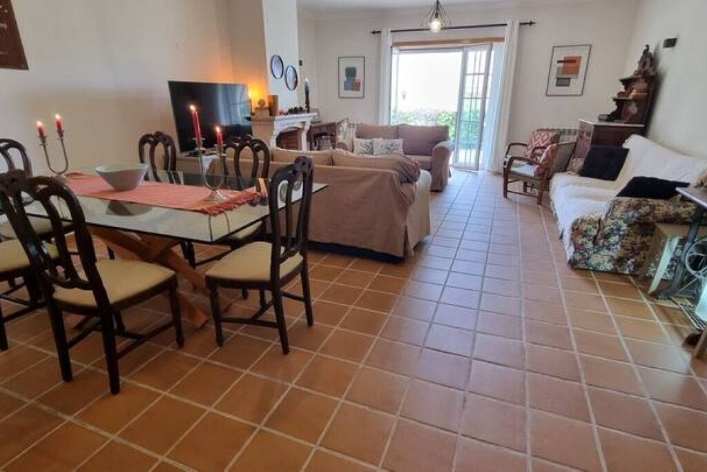 A dining area with a table and chairs, a sofa, and a television in the background.