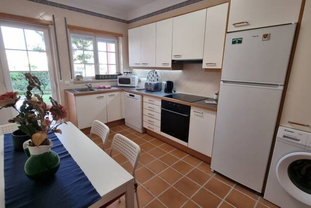 A compact kitchen with white cabinets, a microwave, a dishwasher, and a washing machine.