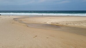 A beach with a curved shoreline and a few people in the distance. - Casa Del Rey - Golf and Beach (Amoreira)