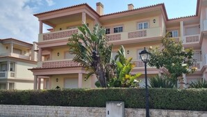 A multi-story building with balconies, a paved area in front, and a street lamp. - Casa Del Rey - Golf and Beach (Amoreira)