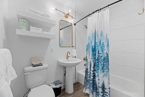 A bathroom with a toilet, sink, and shower curtain.