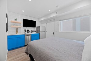 A modern bedroom with a large bed and a kitchenette area.