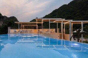 A swimming pool with lounge chairs and a covered seating area, surrounded by greenery. - One Day Tam Coc Retreat (Hoa Lu)