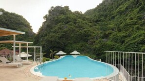 Una piscina circondata da una recinzione bianca, con lettini e ombrelloni.