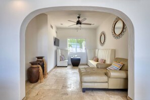 A spacious living area with a sofa, a television, and decorative items. - Casa Maravilla - Walk to Beach & Art District. (San José del Cabo)