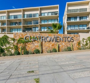 A multi-story hotel with a stone facade and a sign that reads 'CUATROVENTOS'. - Modern 2BR with Ocean Views (Cabo San Lucas)