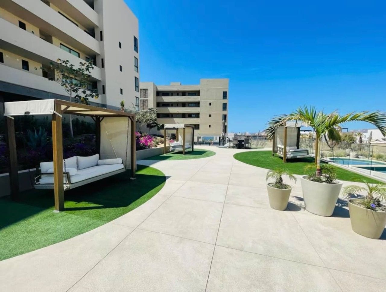 A hotel courtyard with a swing chair, potted plants, a pool, and a building in the background.