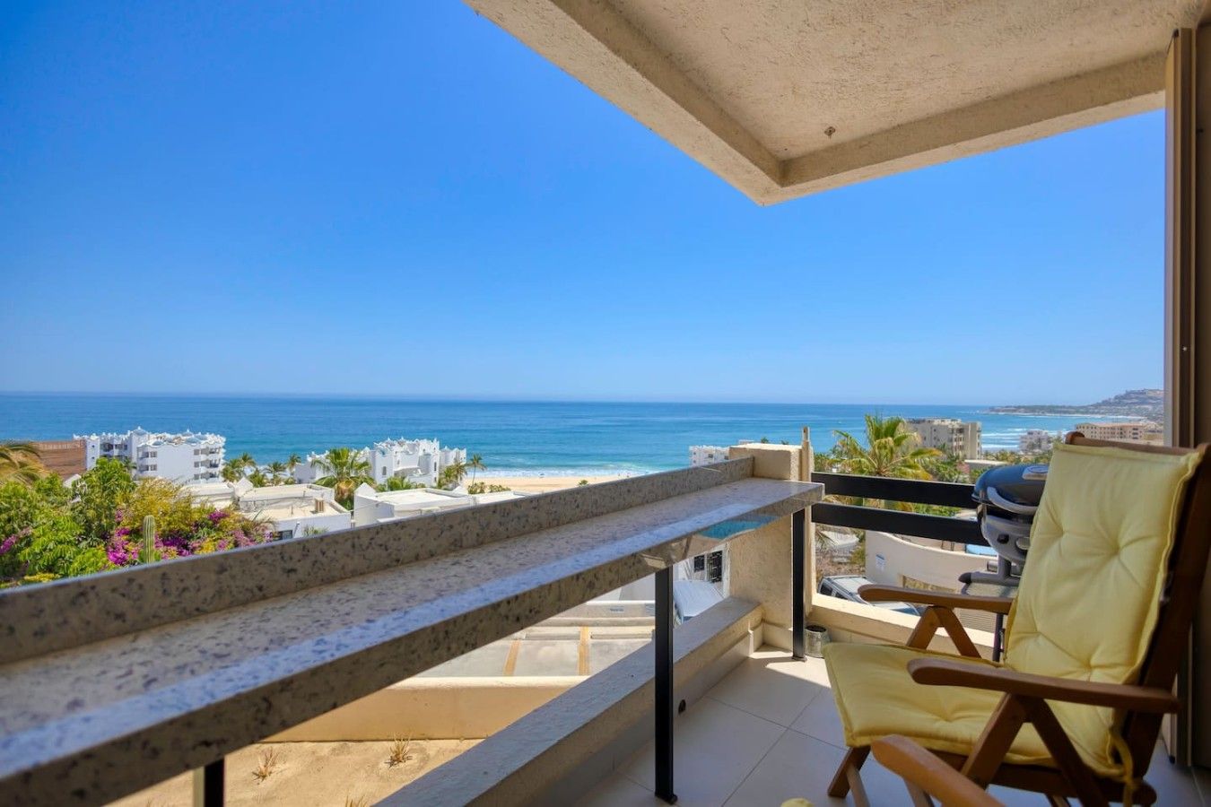 Un balcon avec vue sur la mer, une chaise et une table.